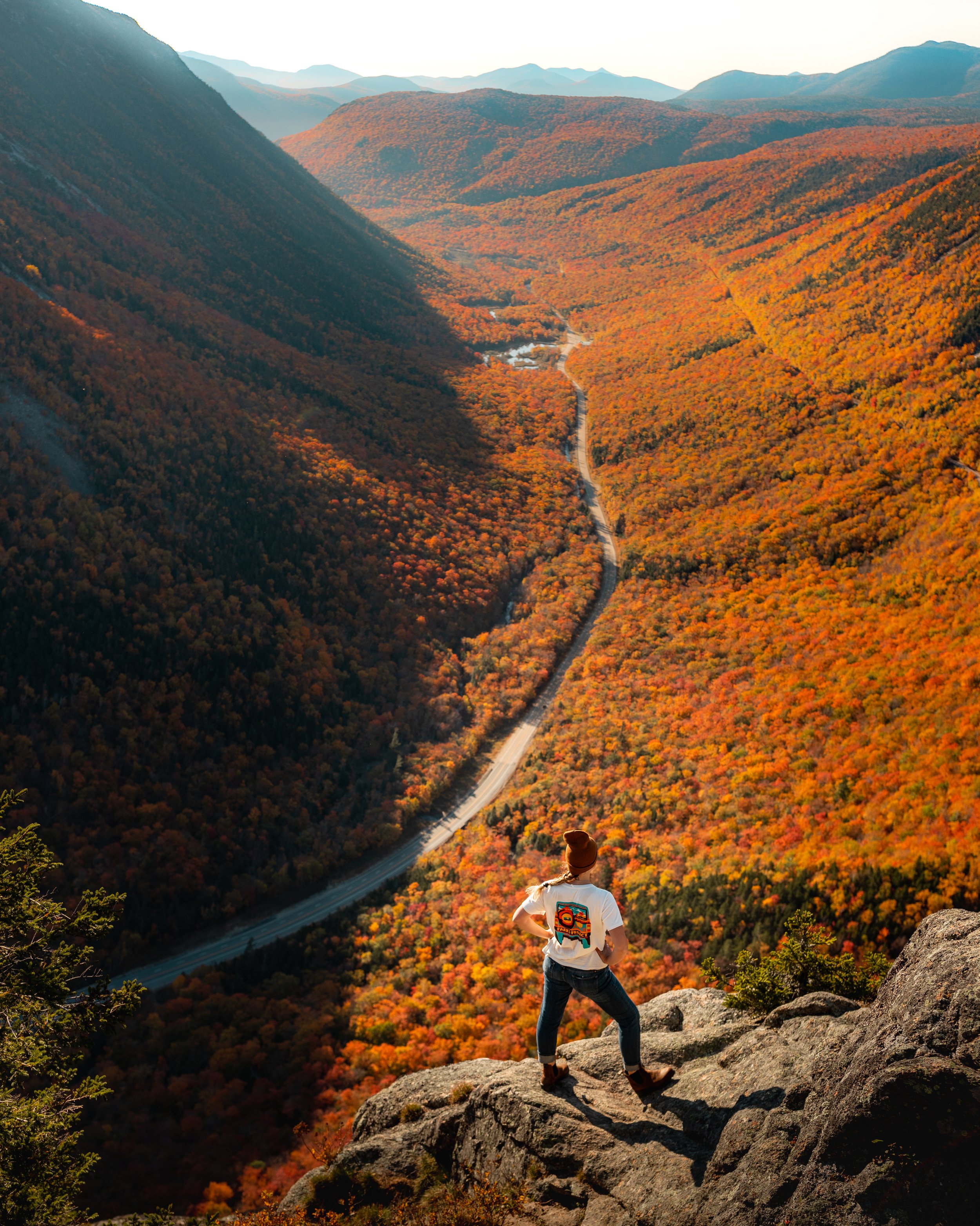 Hiker overlooking fall foliage in the White Mountains